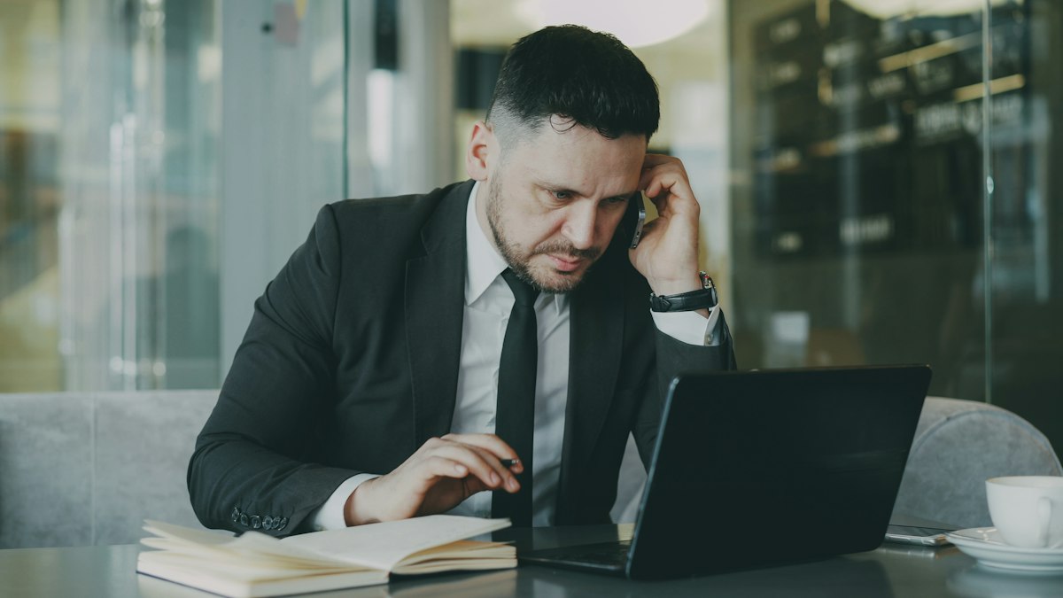 A businessman on a phone call at his laptop
